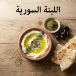 صحن فخاري يحتوي على لبنة سورية بيضاء مغطاة بزيت الزيتون والنعناع المجفف على مائدة فطور سورية تقليدية مع خبز عربي وزعتر وزيتون أسود