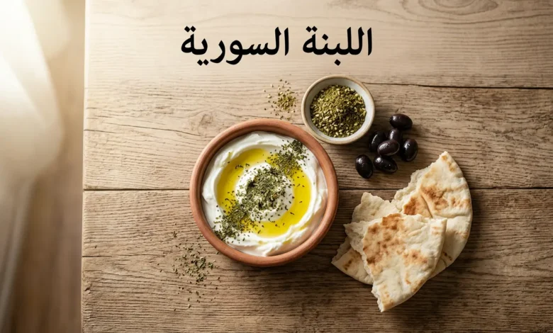 صحن فخاري يحتوي على لبنة سورية بيضاء مغطاة بزيت الزيتون والنعناع المجفف على مائدة فطور سورية تقليدية مع خبز عربي وزعتر وزيتون أسود
