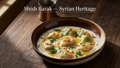 Traditional Syrian shish barak served in a handmade ceramic bowl with yogurt sauce, toasted pine nuts, and clarified butter